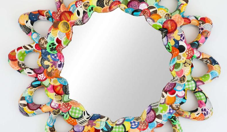 A round mirror outlined with a flower design made of papier-mache.
