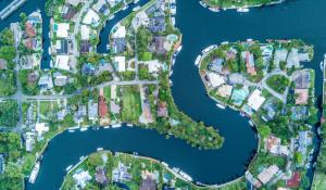 Drone image of a neighborhood in Fort Lauderdale, Florida. A winding river runs through the neighborhood. Homes have dock and boat access to the water.