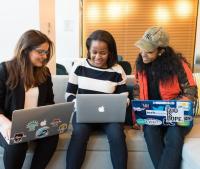 three women sit together with laptops 
