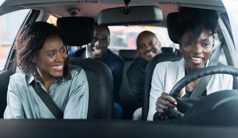 a group of friends take a ride together in the car and they are smiling at each other.