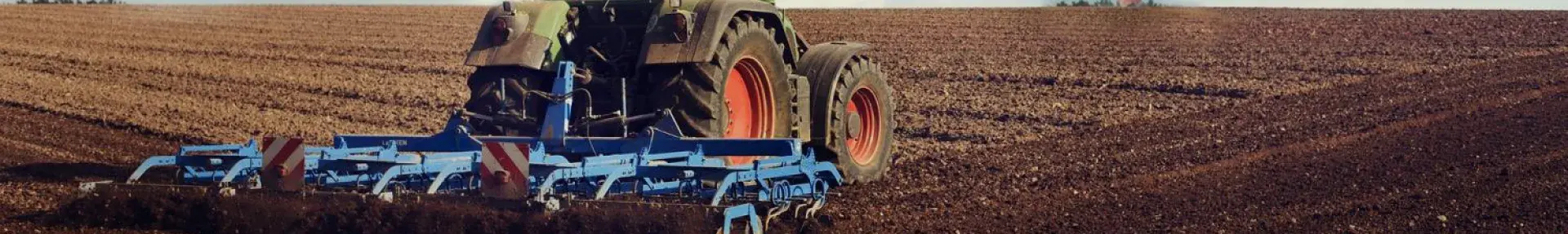 Image: tractor on a field with a wind turbine. Topic: Regenerative Agriculture.