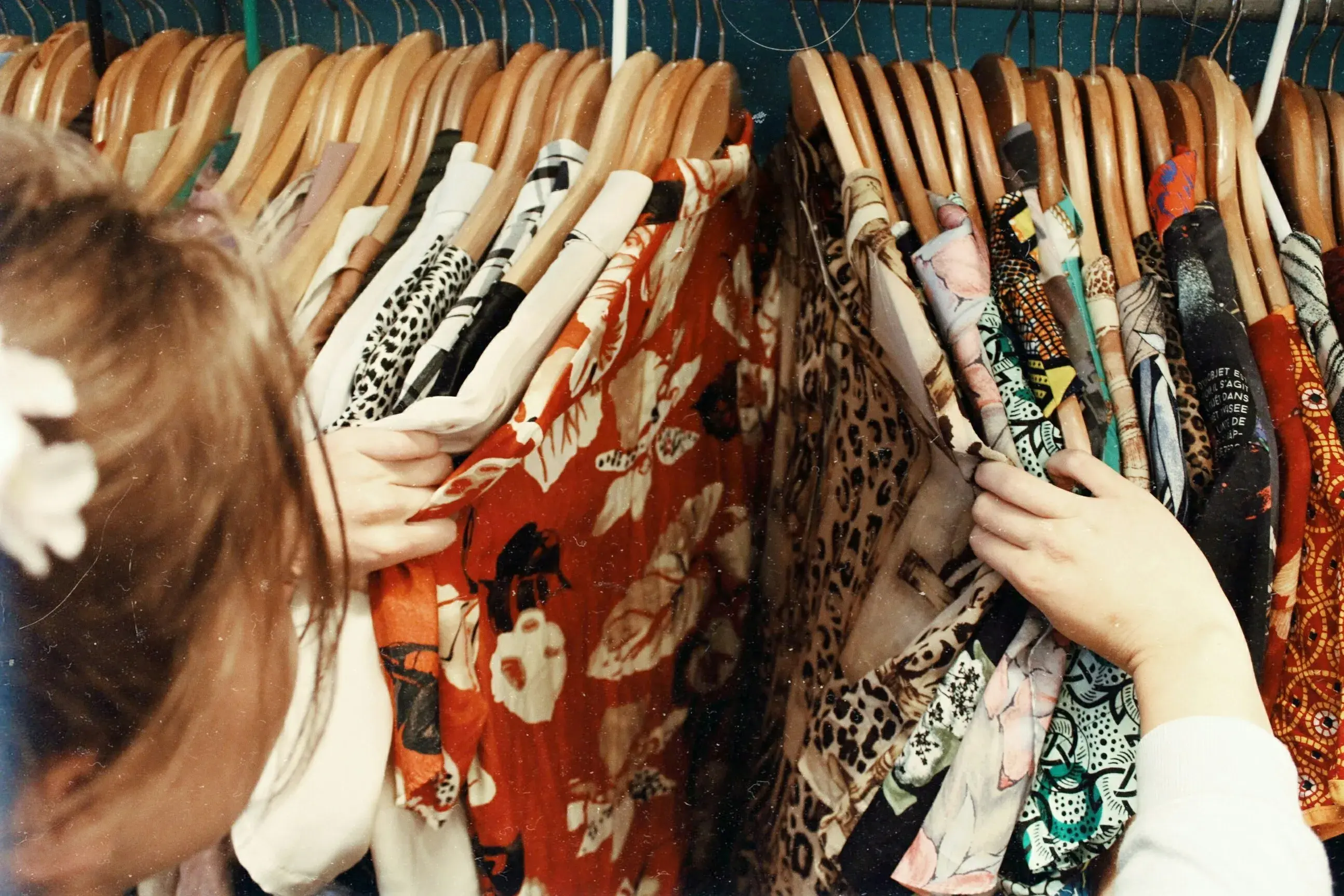 A woman browsing colorful clothes hanging on a rack. 