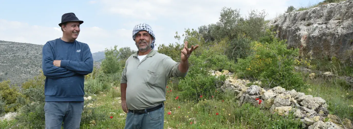 Nasser Abufarha and a Palestinian farmer talking in a field.