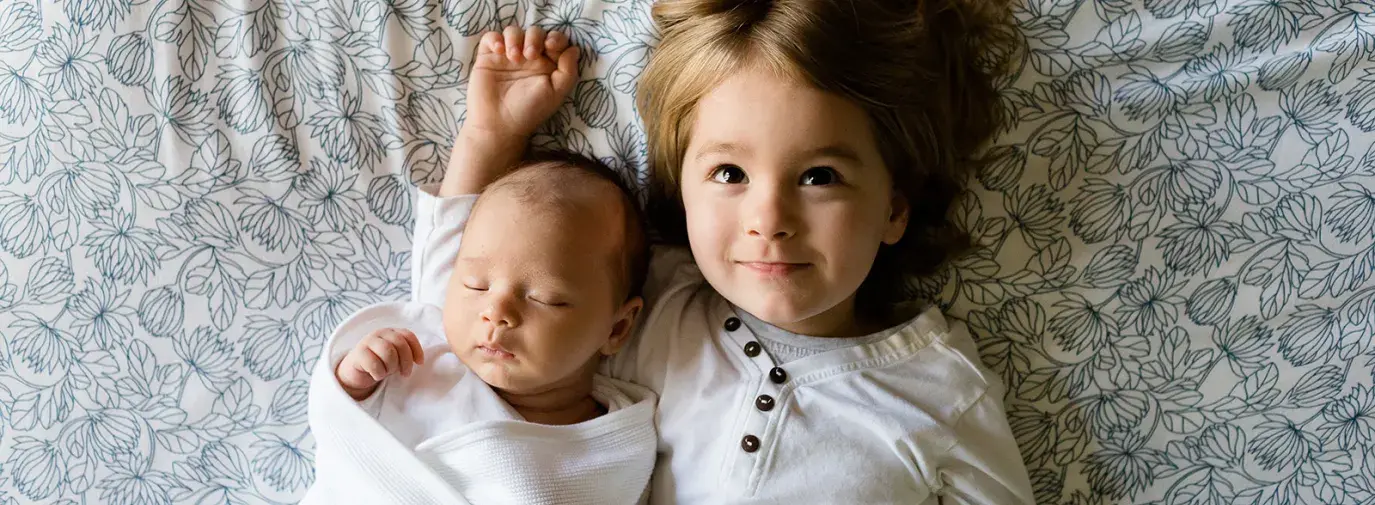 Image: two kids lie on a bed. Title: Eco-Friendly Children's Clothing
