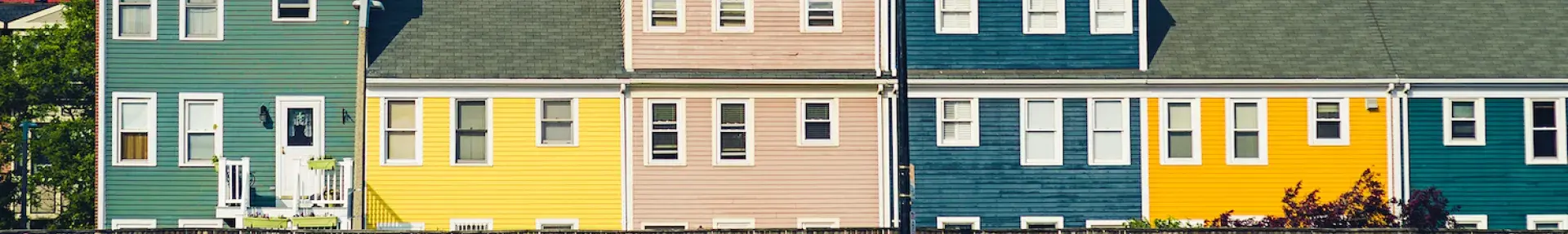 Image: person walking by row of homes. Topic: Green Home.