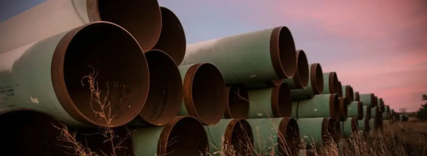Image: pipes stacked in a field. Topic: Break Up With Your DAPL-Supporting Bank.