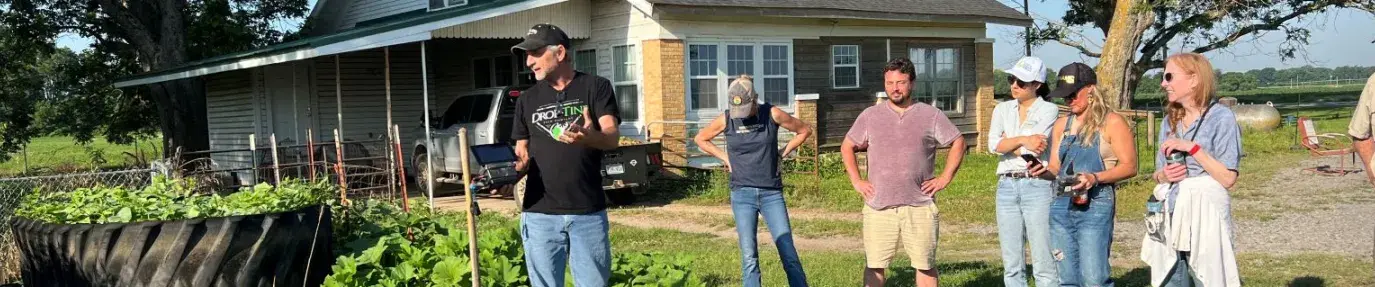 seven people standing outside a garden in the morning sunlight