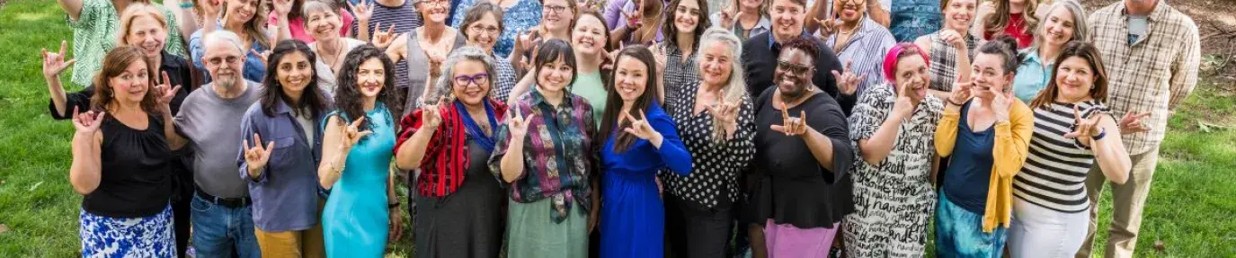 three rows of green america staff making the hand sign for I Love You in ASL